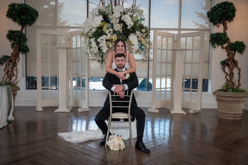 Danielle and Michael are captured in a joyful, posed moment inside an elegant hall during their wedding celebration.
