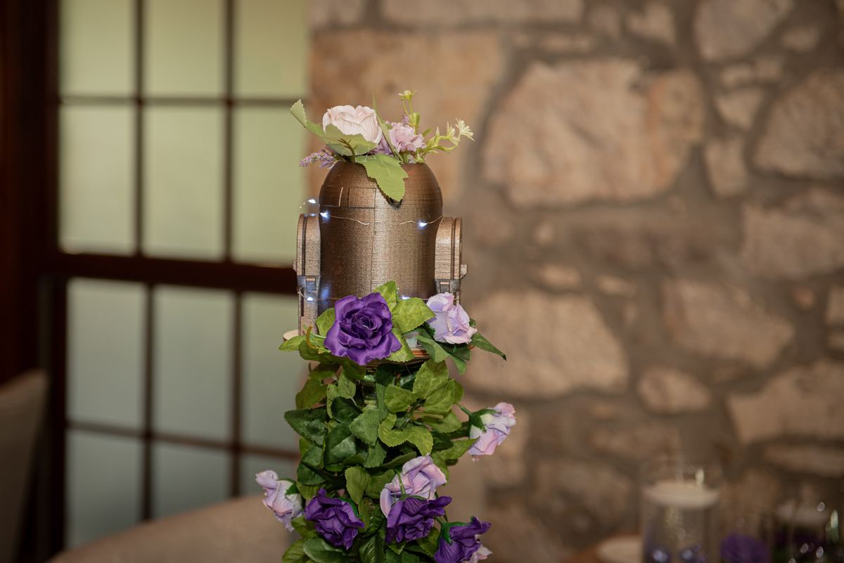 A vintage microphone surrounded by purple and pink roses against a rustic stone wall and shoji window.