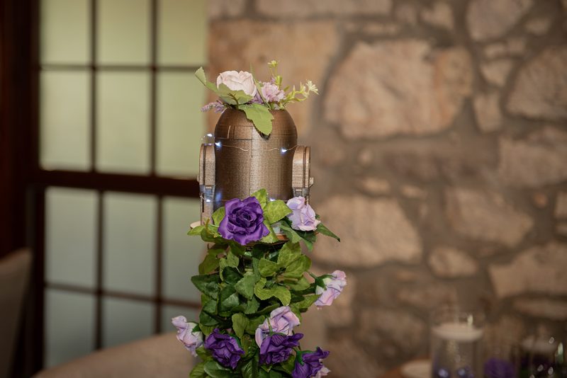 A vintage microphone surrounded by purple and pink roses against a rustic stone wall and shoji window.