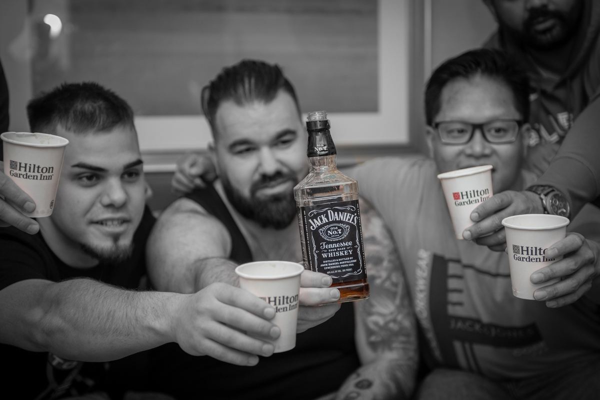 Men in casual attire raising Hilton Garden Inn cups and toasting with Jack Daniel’s, creating a warm atmosphere.