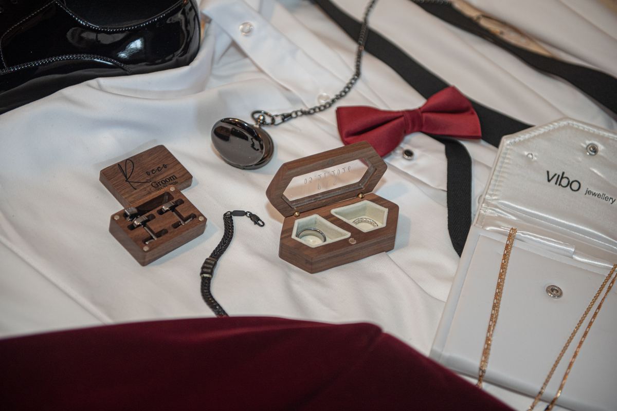 Groom's wedding accessories laid out before the ceremony, including rings, watch, bow tie, and shirt.