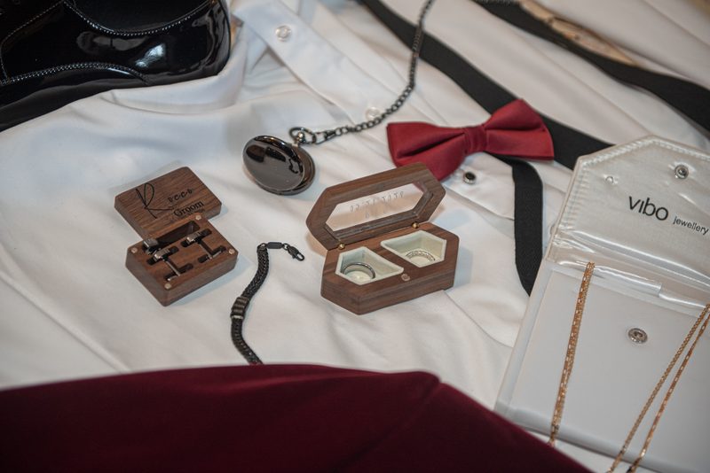Groom's wedding accessories laid out before the ceremony, including rings, watch, bow tie, and shirt.