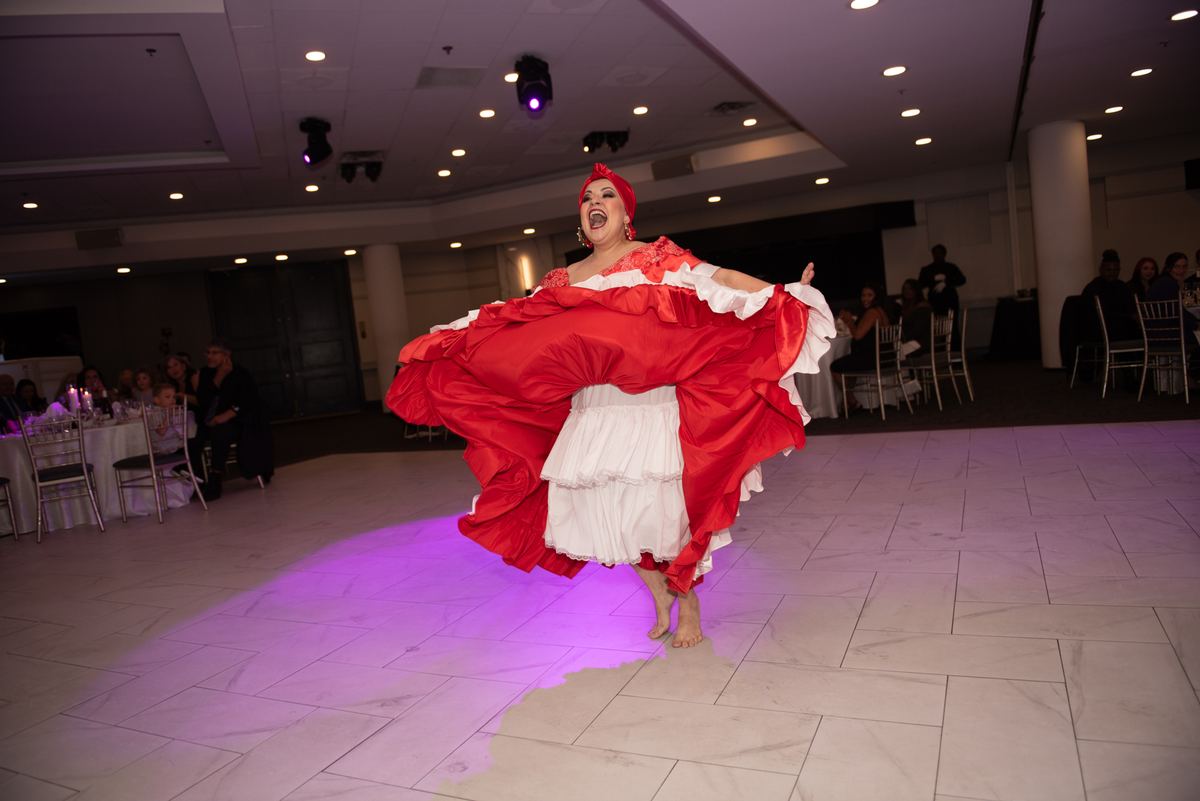 A flamenco dancer in red and white performs passionately on a tiled floor, her skirt swirling as she leaps.