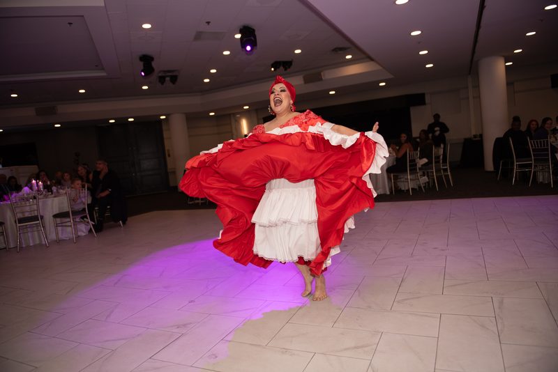 A flamenco dancer in red and white performs passionately on a tiled floor, her skirt swirling as she leaps.