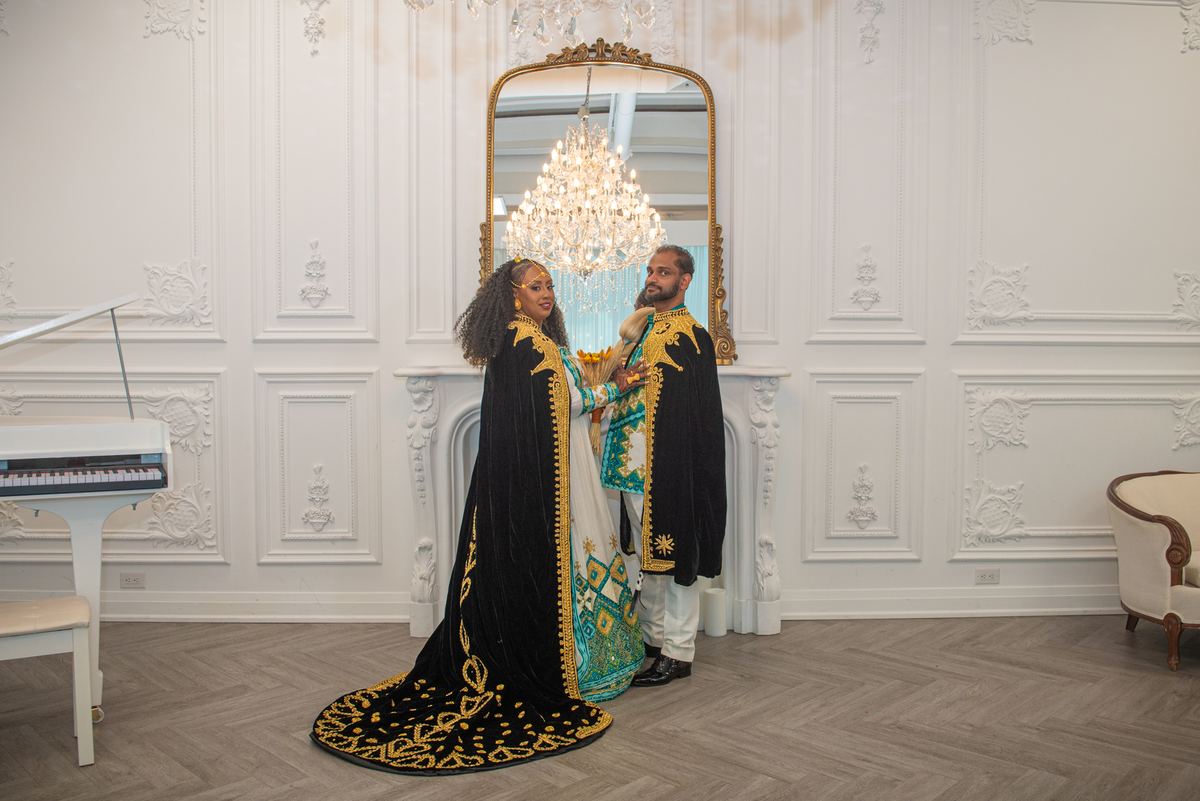 Salem and Shannon stand close in ornate black and gold robes, Salem smiling warmly as she touches Shannon's arm.