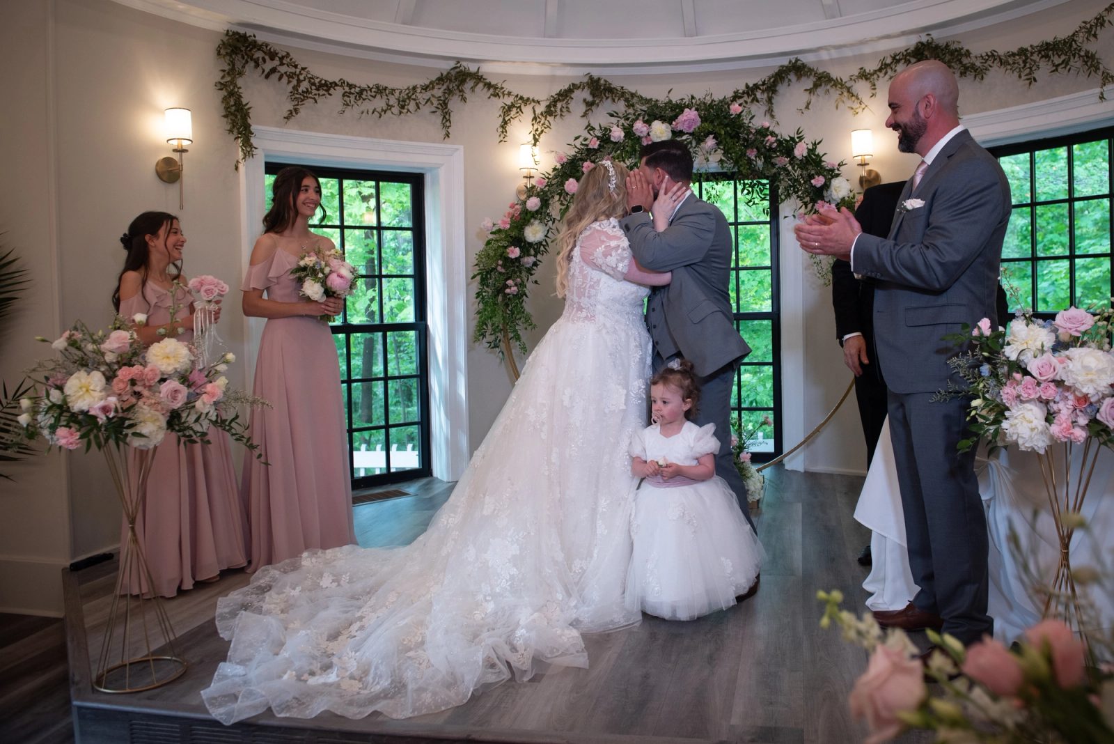 Josianne and Duarte share a passionate kiss at the altar, surrounded by floral arrangements and greenery.