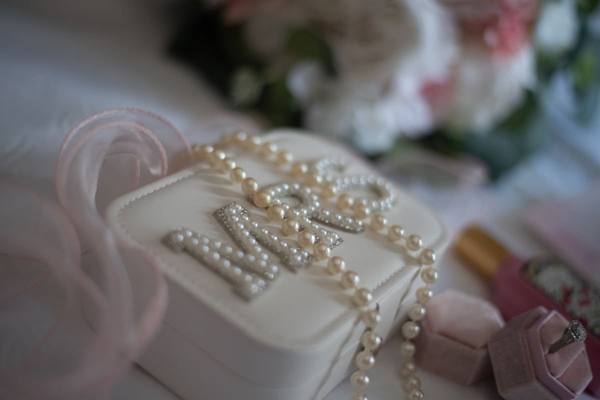 A white pearl-adorned jewelry box with delicate pink ribbon and ring holder, creating a romantic atmosphere.