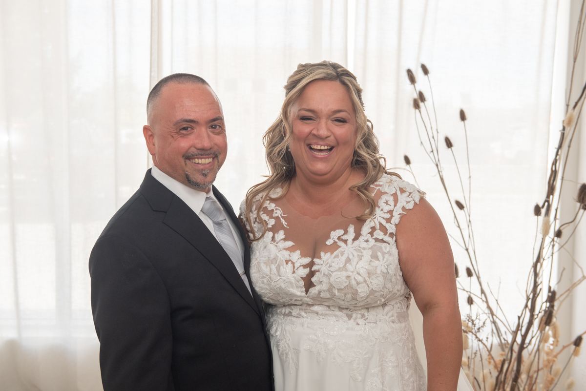 Candace and Felice smile broadly at the camera, their happiness evident in the candid moment captured during their wedding.