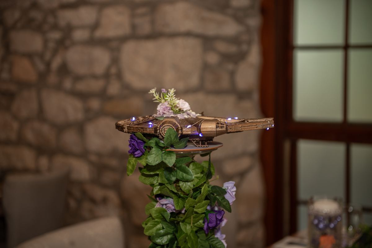 A model of the Millennium Falcon decorated with lights and flowers sits at the center of a table, creating a warm atmosphere.