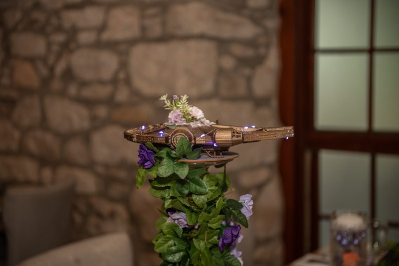 A model of the Millennium Falcon decorated with lights and flowers sits at the center of a table, creating a warm atmosphere.