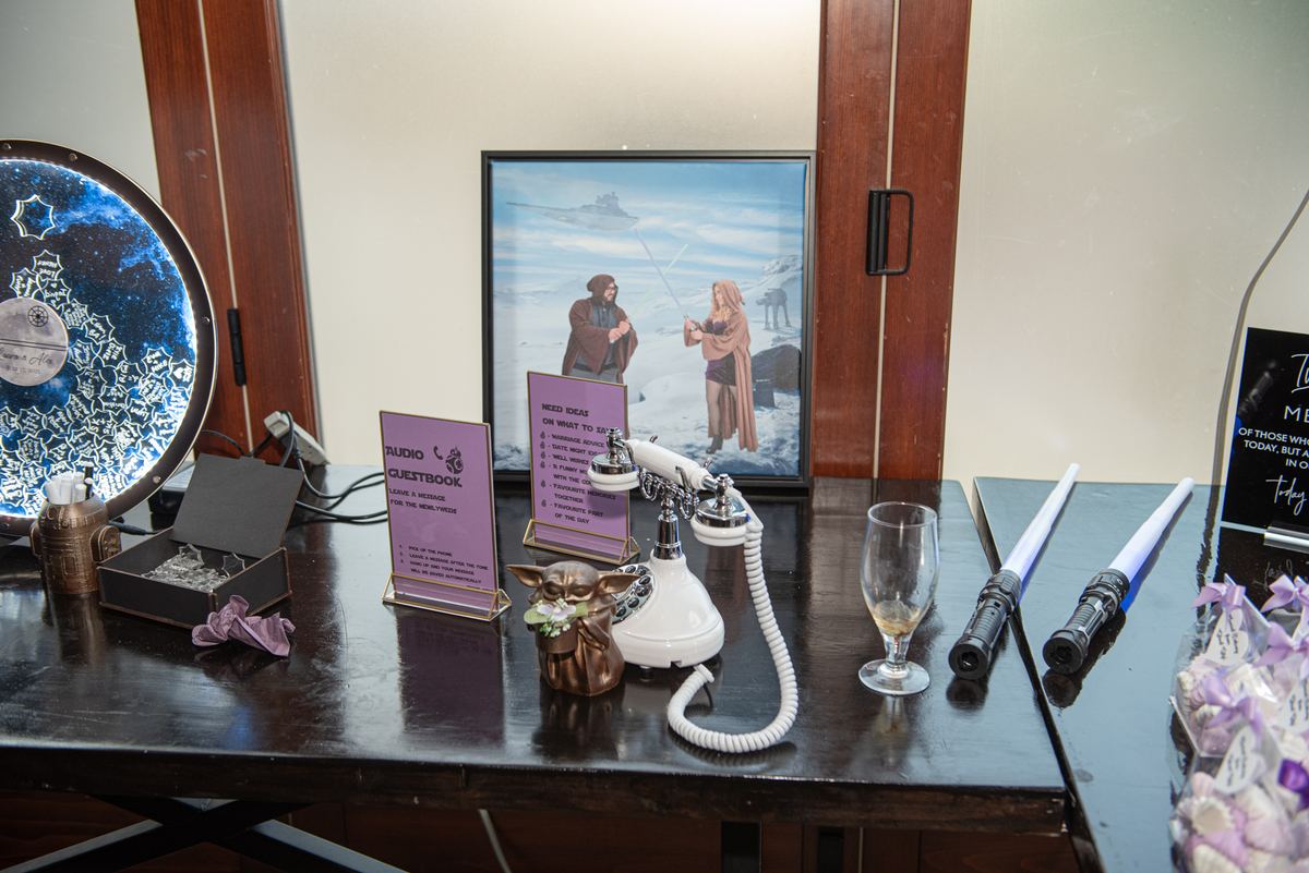 A themed Star Wars wedding station with a vintage phone, lightsabers, Yoda figurine, and Death Star mirror.