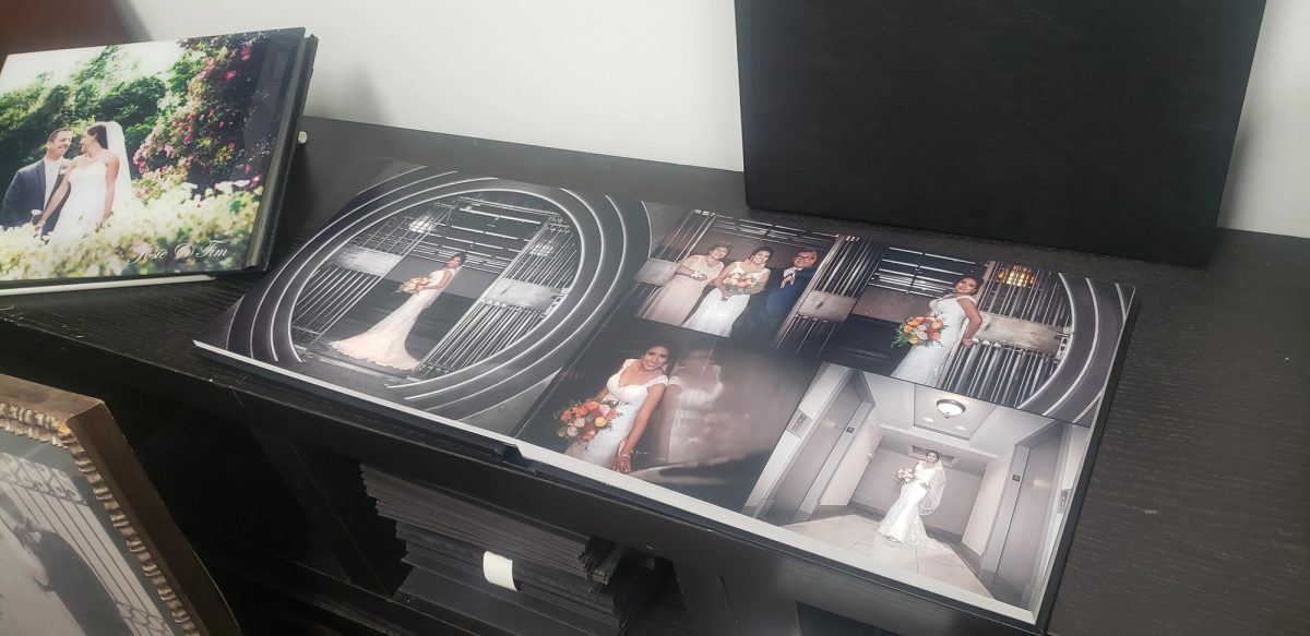 An open layflat wedding album on a shelf, a bride photographed in a bank-vault door across the spread