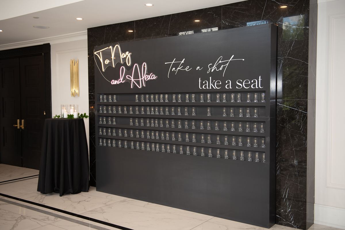 A black marble wall with a shot wall installation and seating area, illuminated by ambient lighting.
