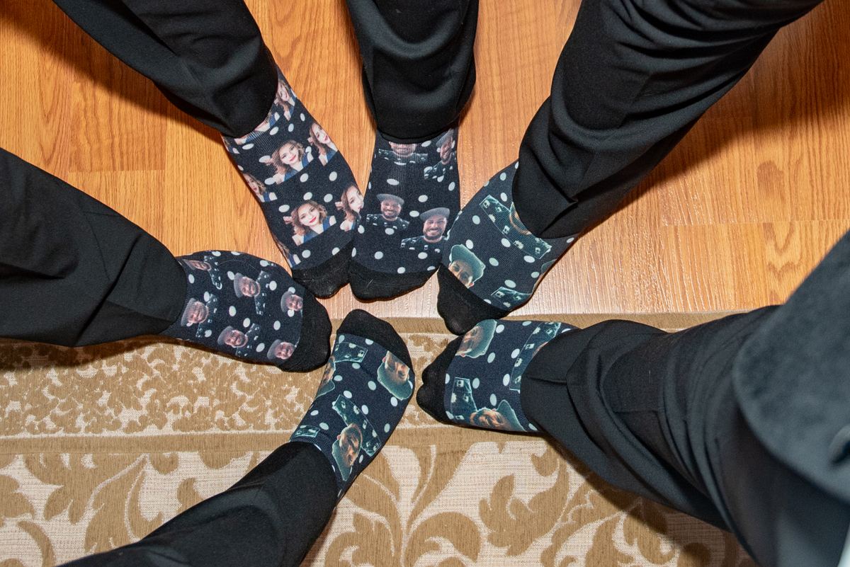 Feet in black socks with smiling faces gather in a circle on a wooden floor, decorated with a patterned rug.