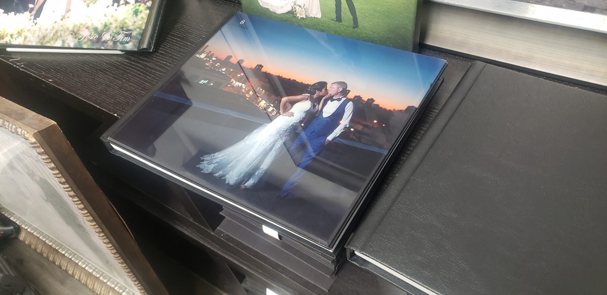 A wedding album with a glossy acrylic photo cover, lying on a dark shelf