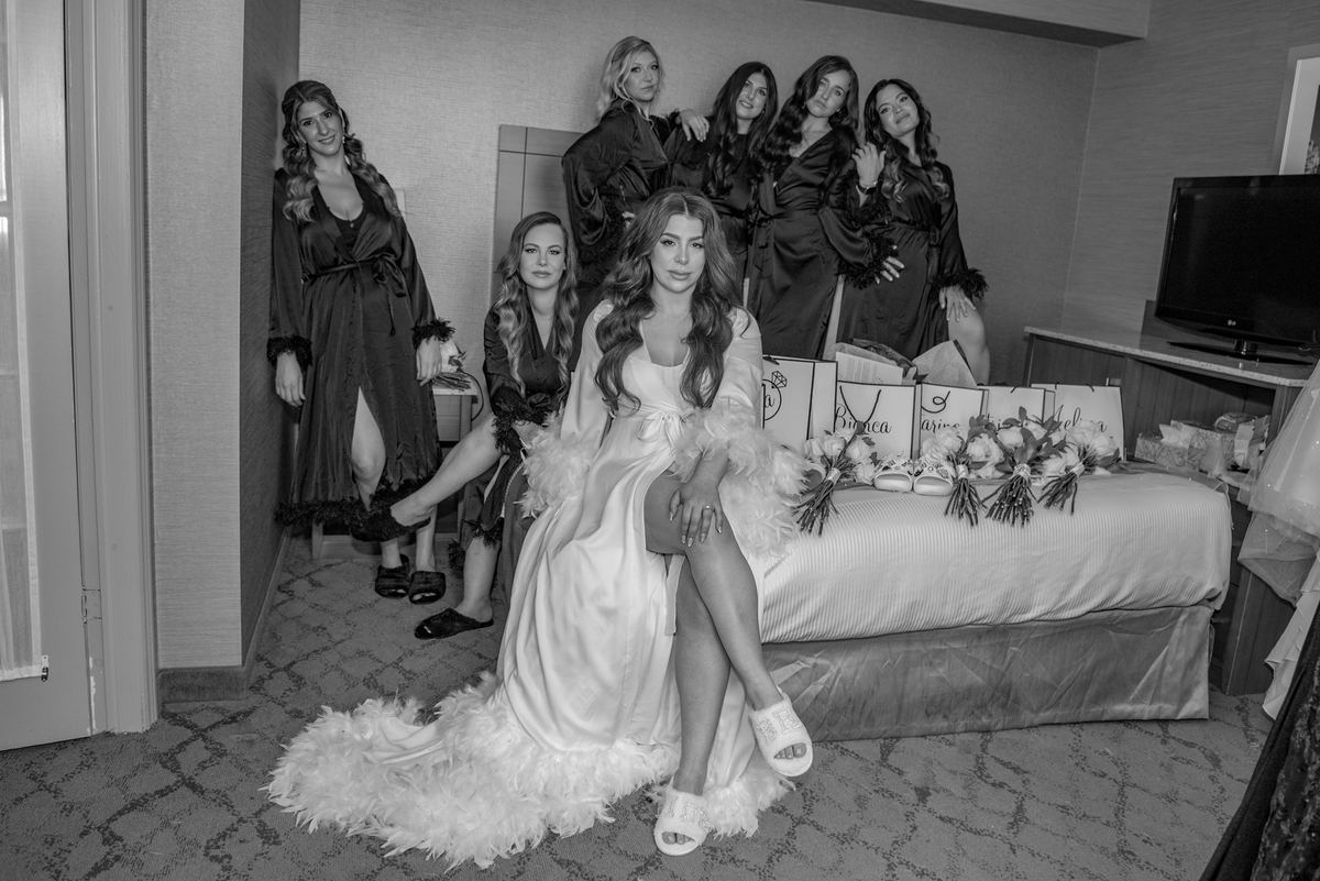 A black-and-white photo from Erica's wedding shows the bride sitting on a hotel bed with her bridesmaids.