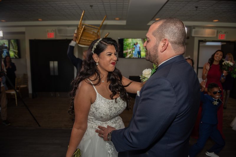 The bride and groom exchange a tender look at their lively wedding reception, surrounded by celebrating guests.