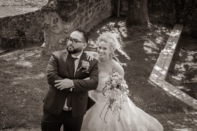 A bride and groom stand in an ancient courtyard, the bride smiling as she leans on her thoughtful partner.