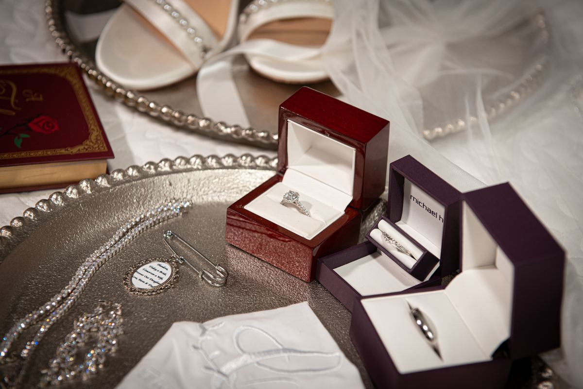 Silver tray holds wedding rings, veil, and pearl sandals in soft light during pre-ceremony preparations.