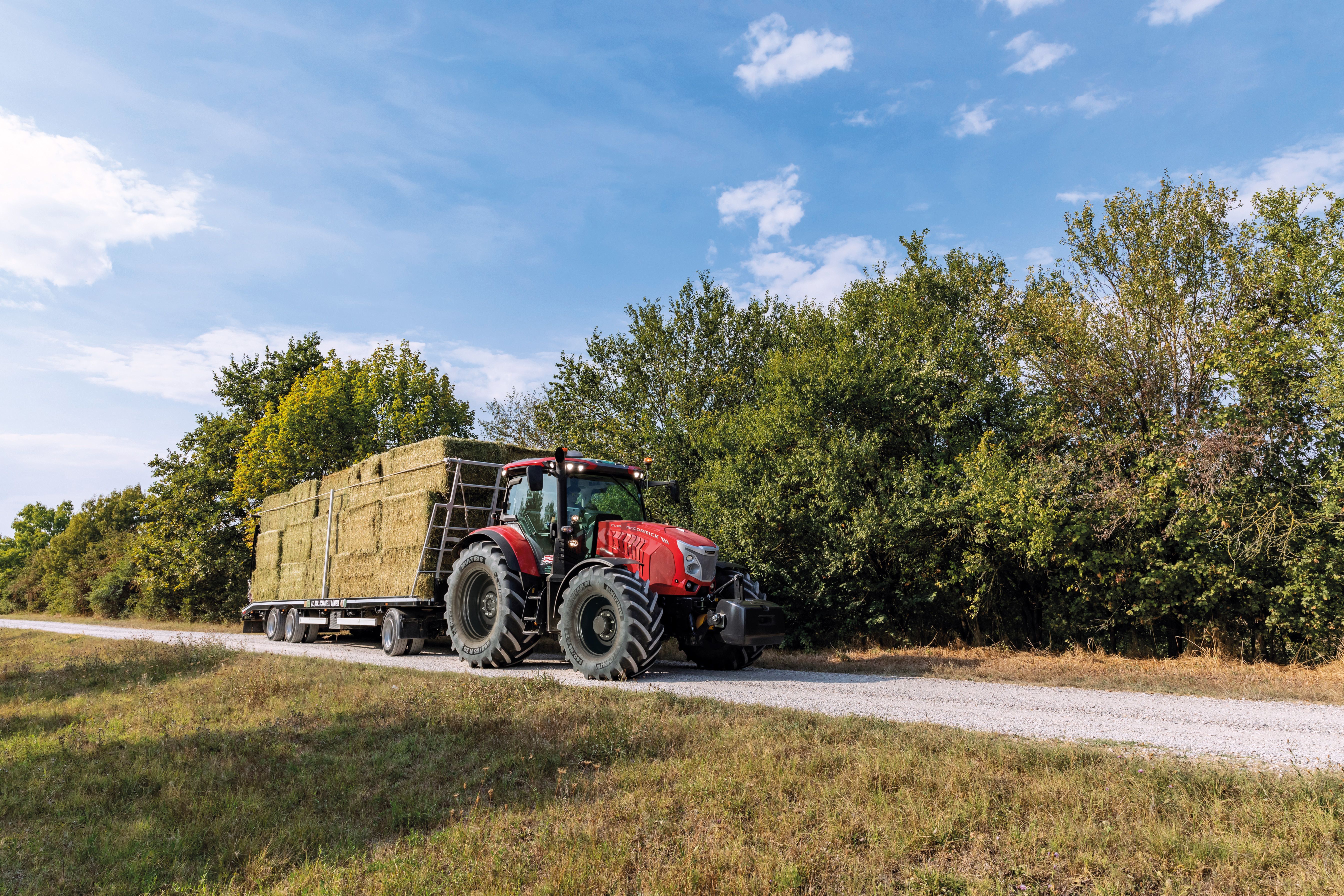 McCormick tractor transporting a trailer of bales