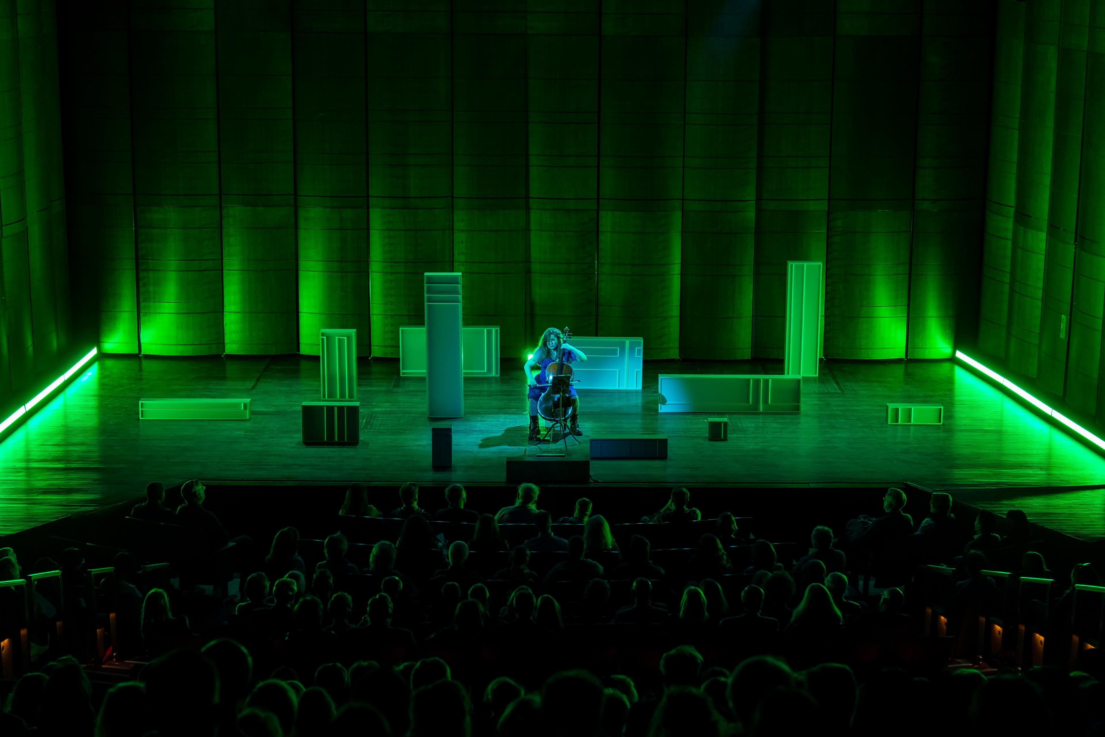 Cellist Alisa Weilerstein performs in a green haze amongst set boxes