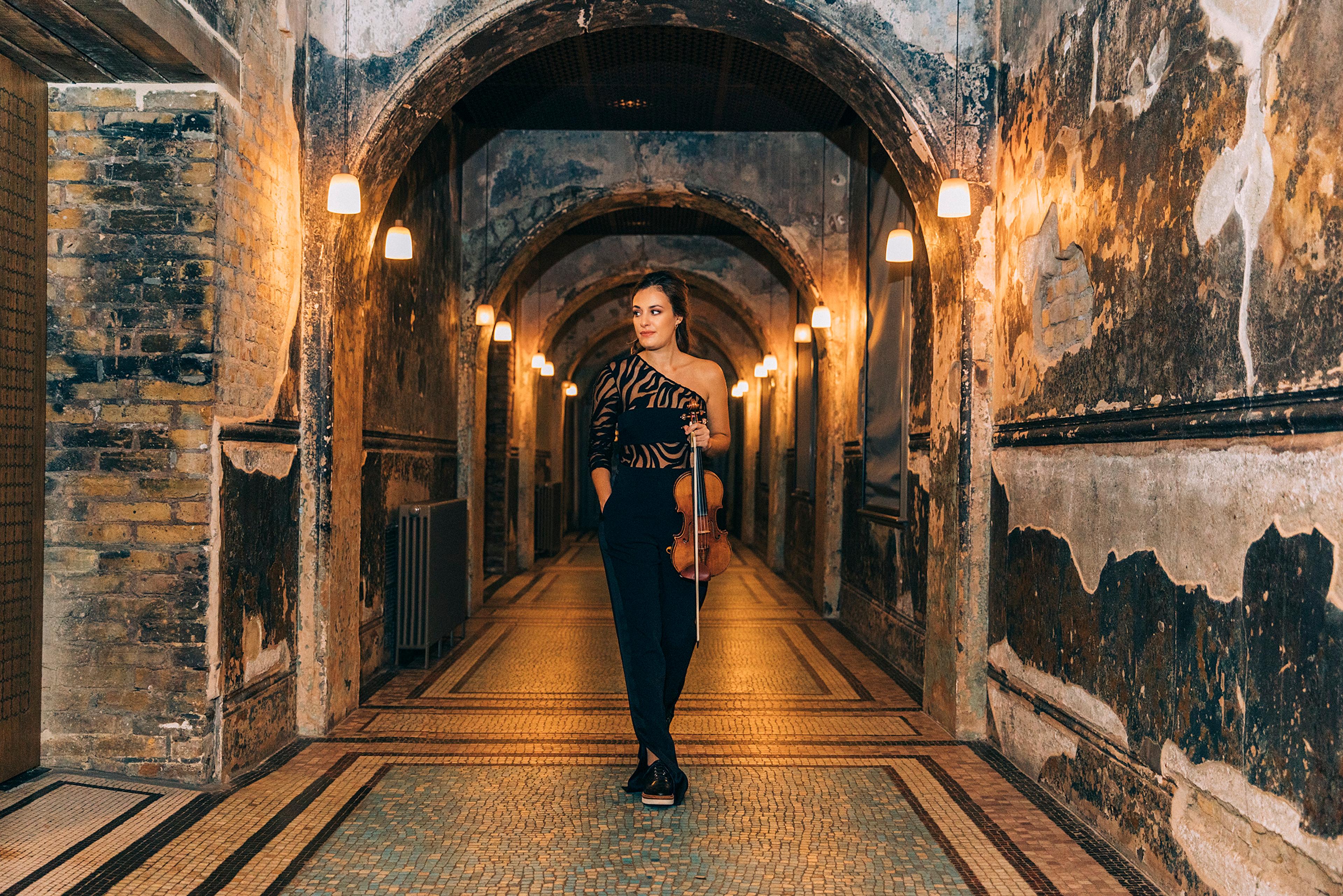 Nicola Benedetti stood in a warmly lit corridor holding her violin in one hand