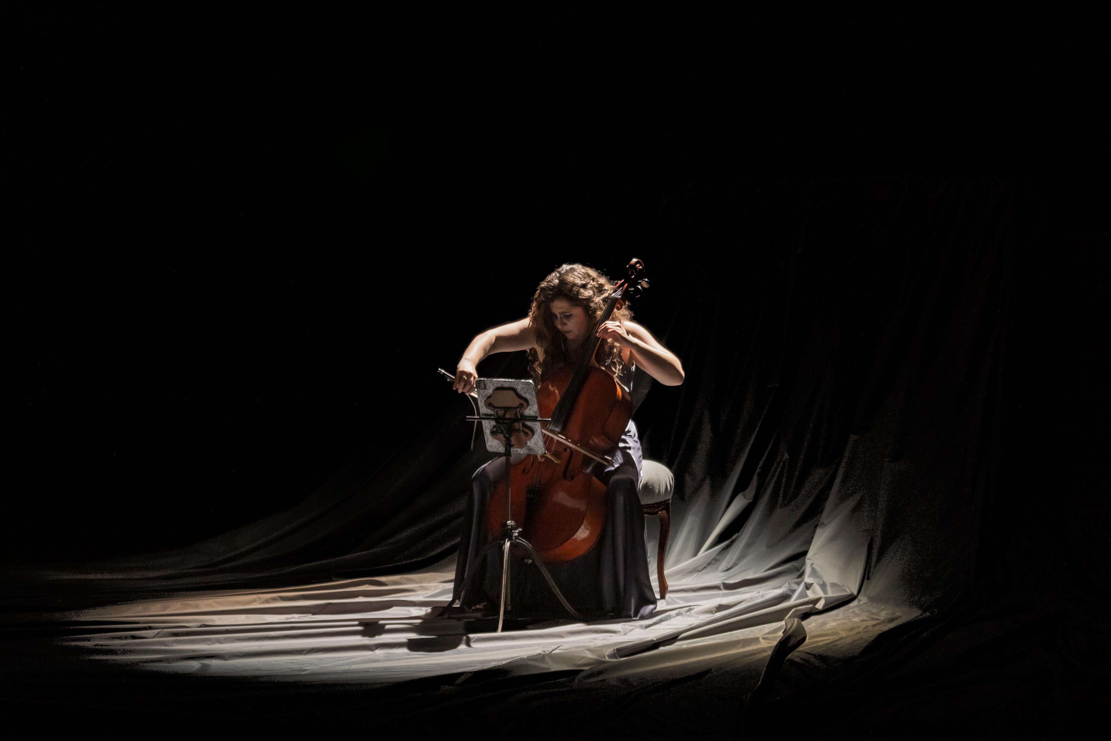 Alisa Weilerstein performing against a dark material backdrop