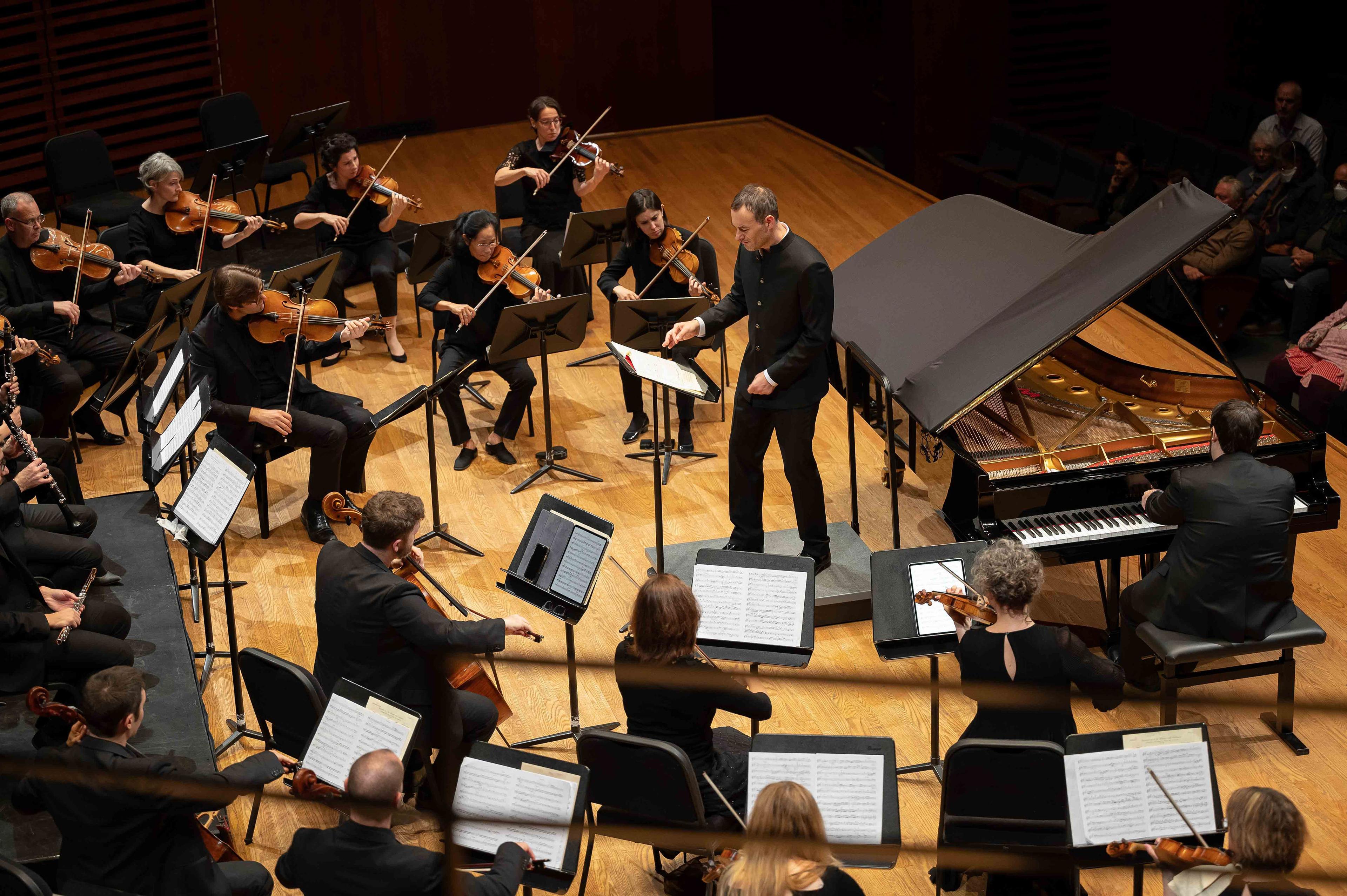 Musicians of the orchestra playing on stage with conductor and pianist