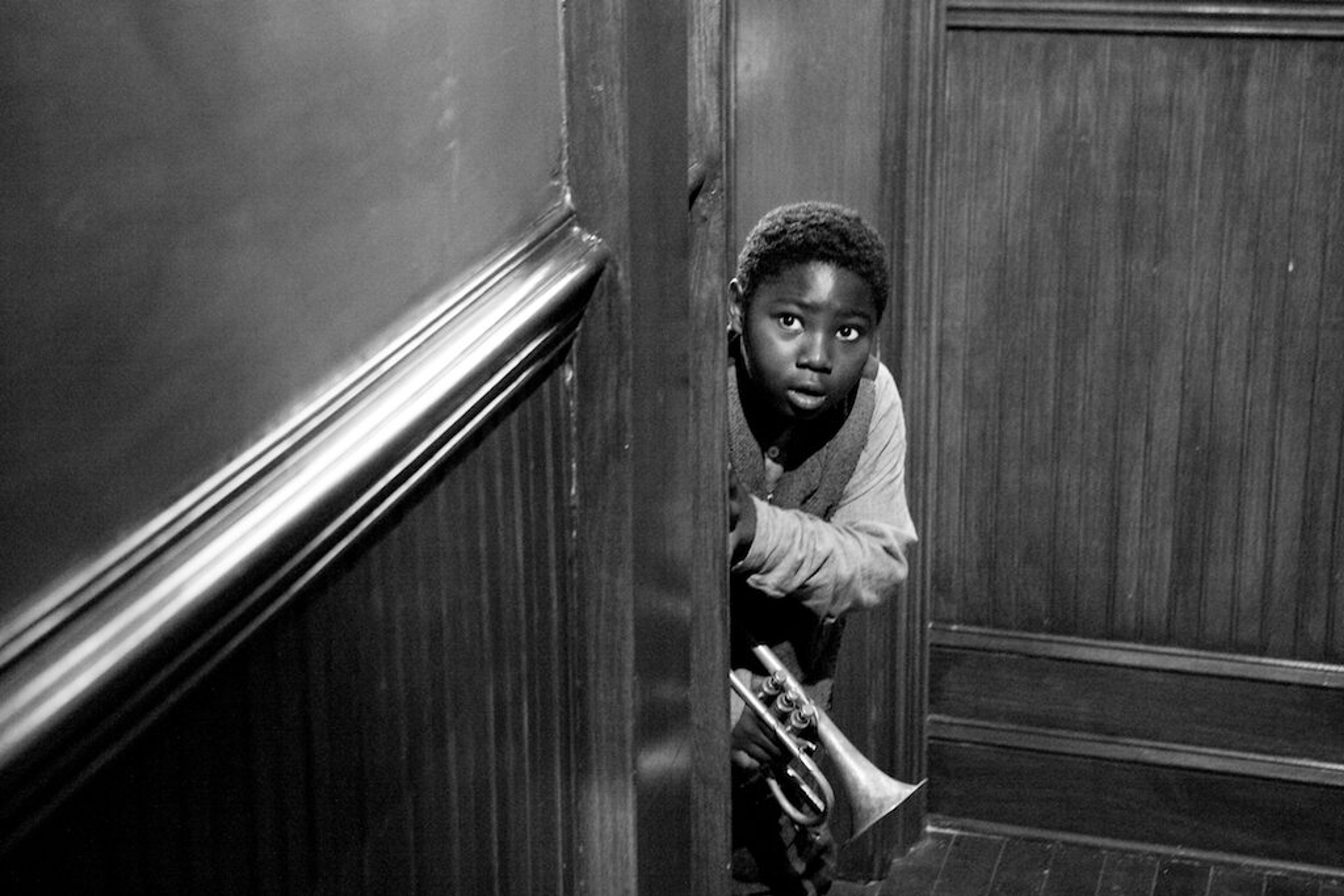 Louis Armstrong as a young boy peeking around a corner