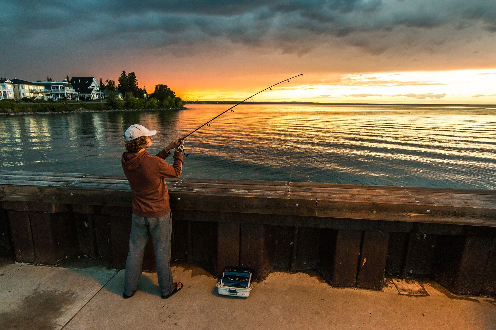 Fisherman fishing off a dock. Cold Lake, Northern Alberta.