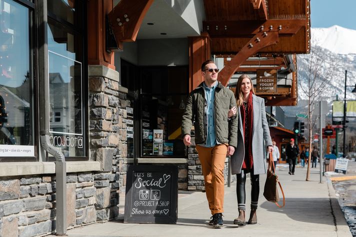 Couple shopping in downtown Canmore with snow-capped mountains