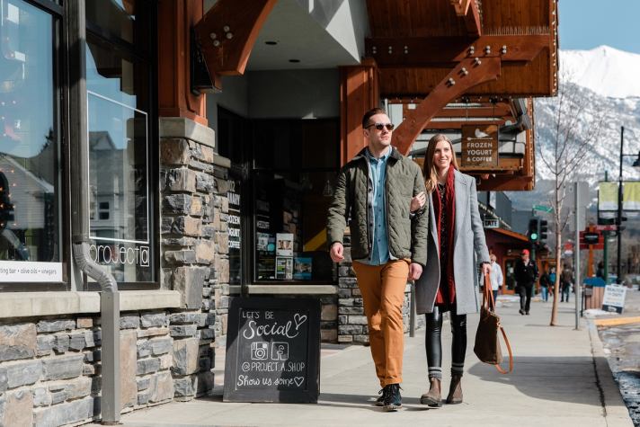 Couple shopping in downtown Canmore with snow-capped mountains