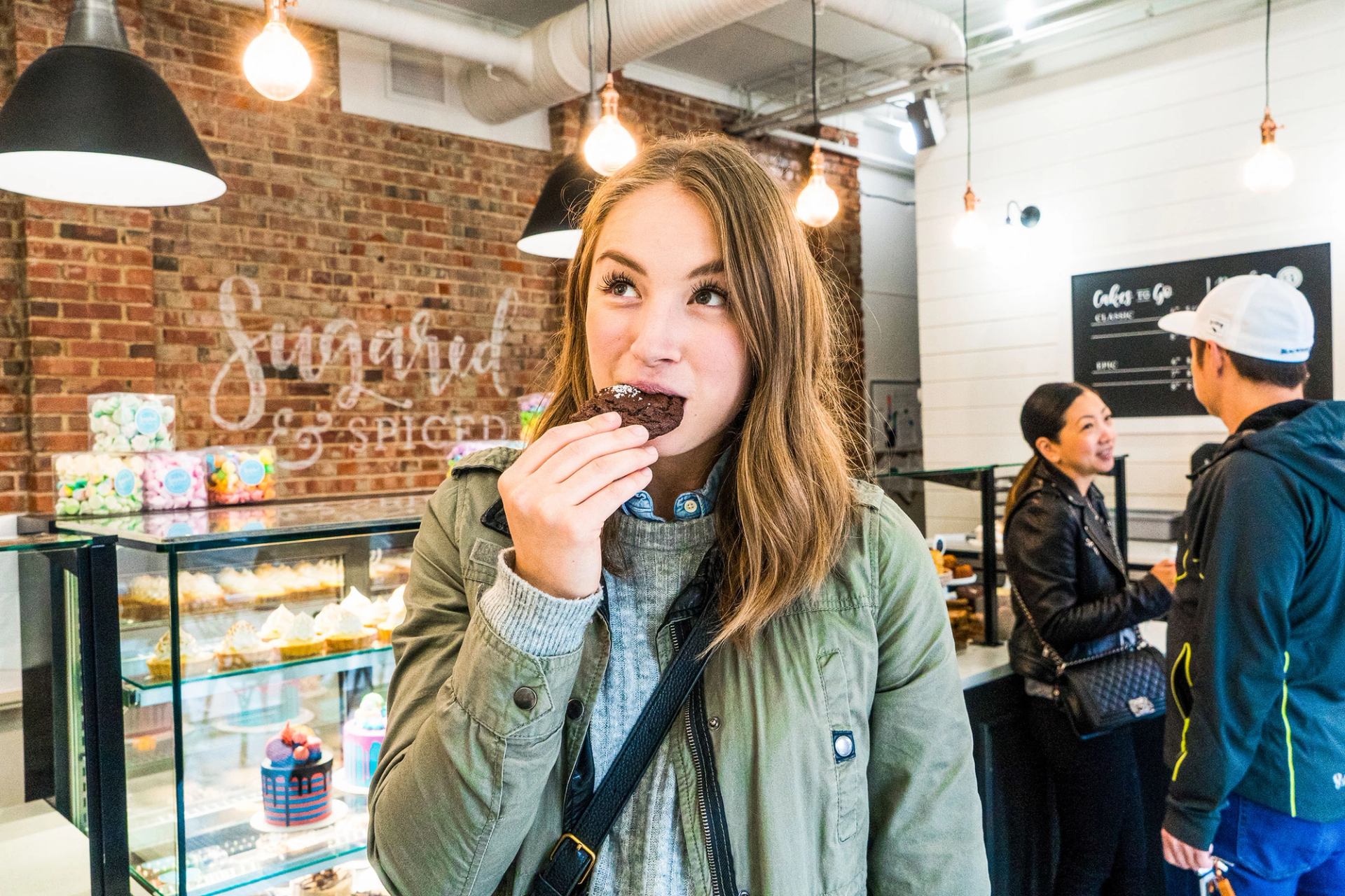A woman eats a cookie in a dessert shop