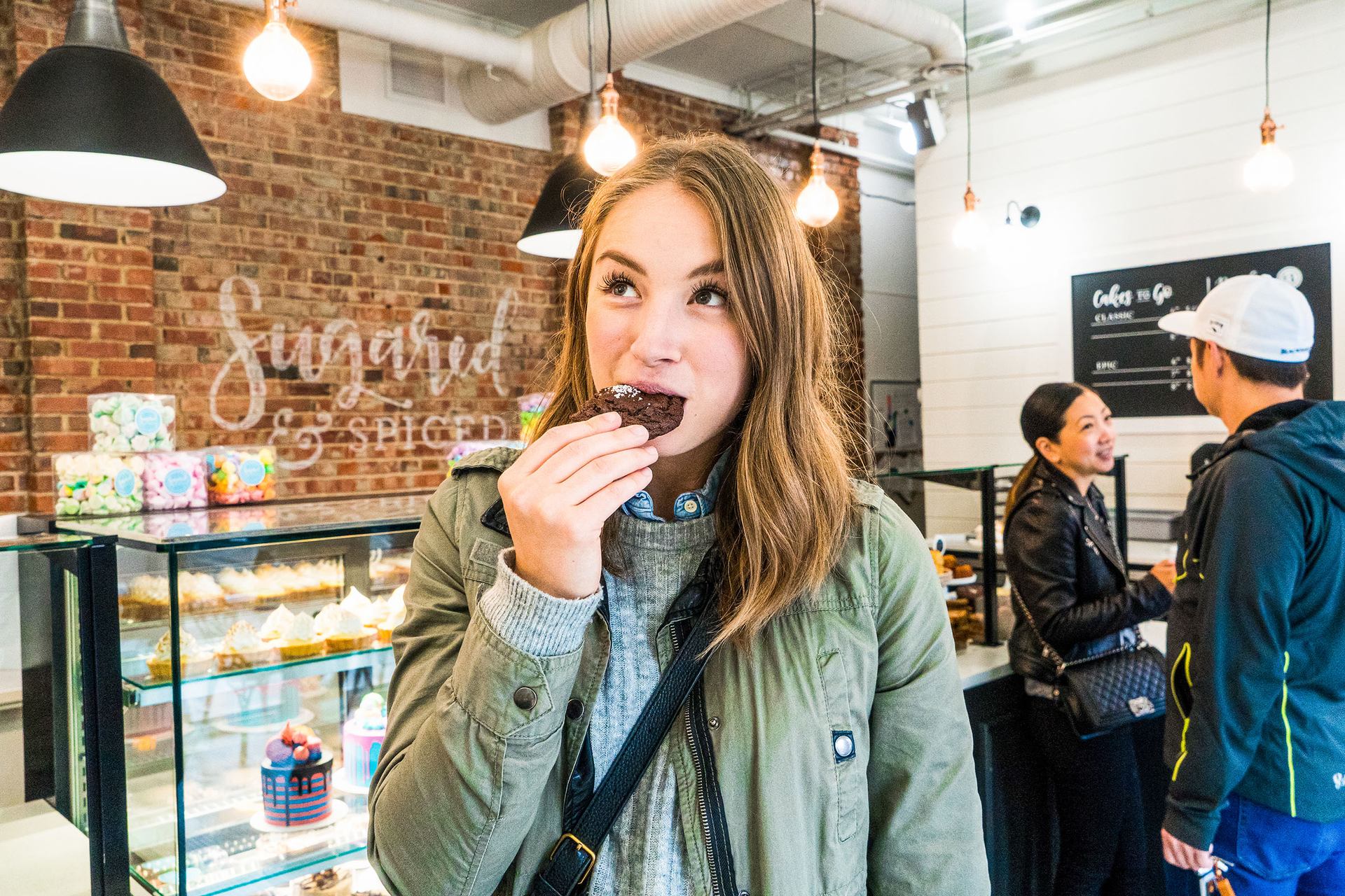 A woman eats a cookie in a dessert shop