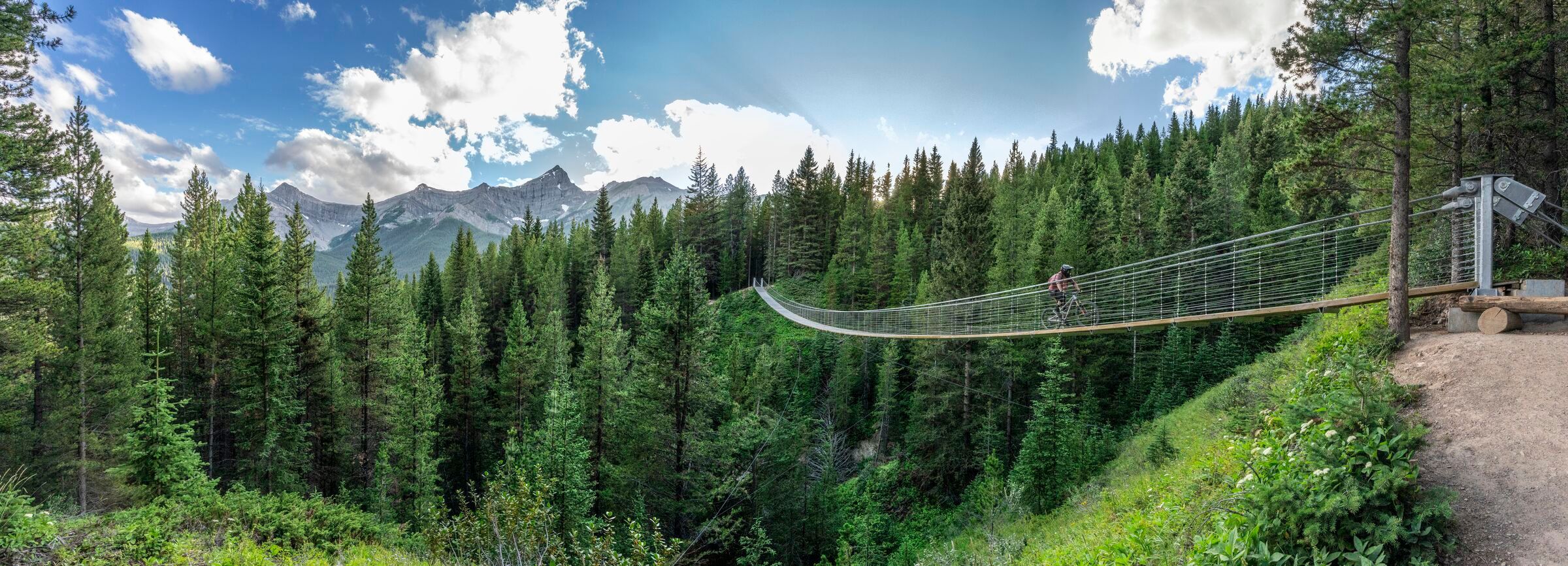 Mountain biking crossing the Blackshale Suspension Bridge in Kananaskis