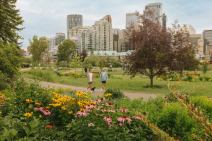 Two men walking dog down path with downtown Calgary in the background