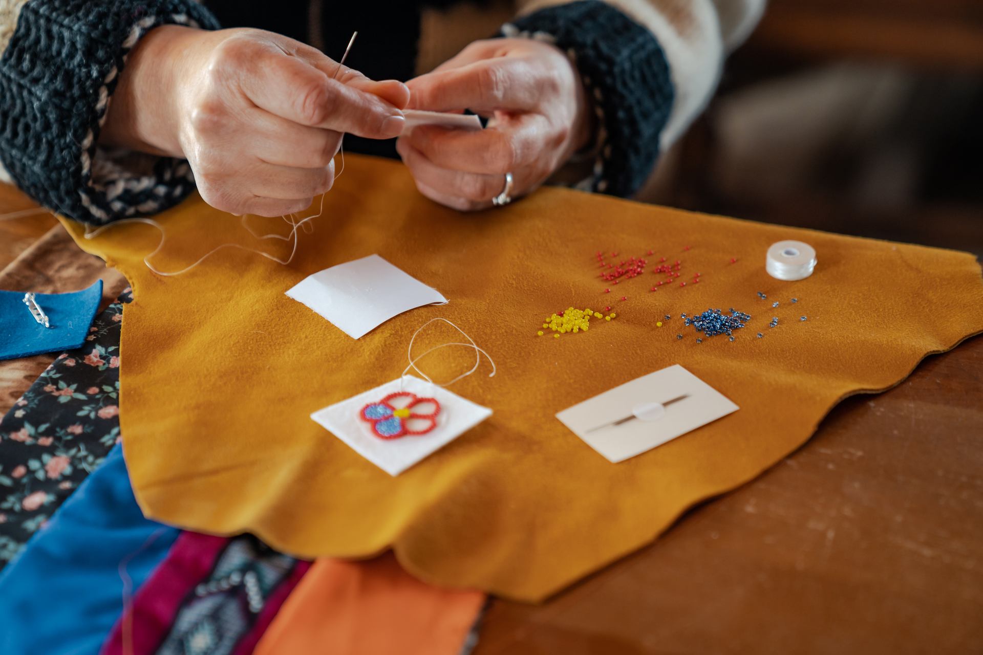 Close up on hands sewing and beading Indigenous art.