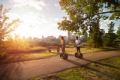 Two people ride Segways down a path as the sun goes down, Edmonton skyline in the background
