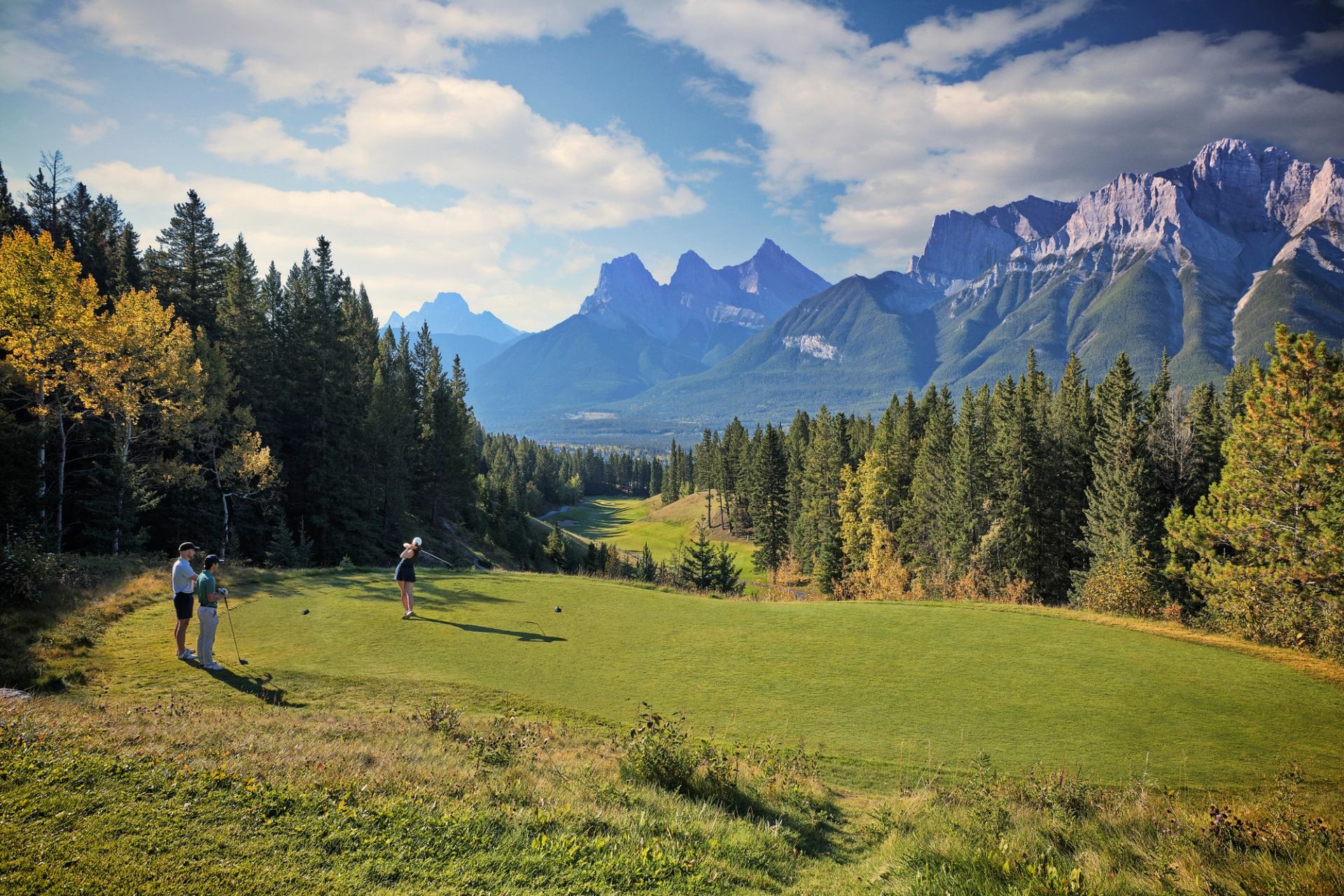A group of golfers on the green with mountain views in the background at Silvertip Resort in Canmore.