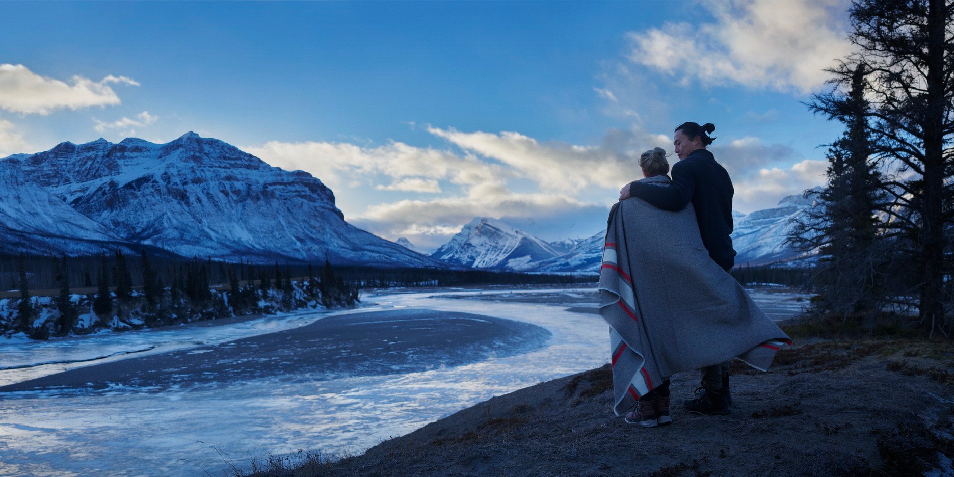 Couple taking in the view of the Alberta mountains with a blanket wrapped around them.