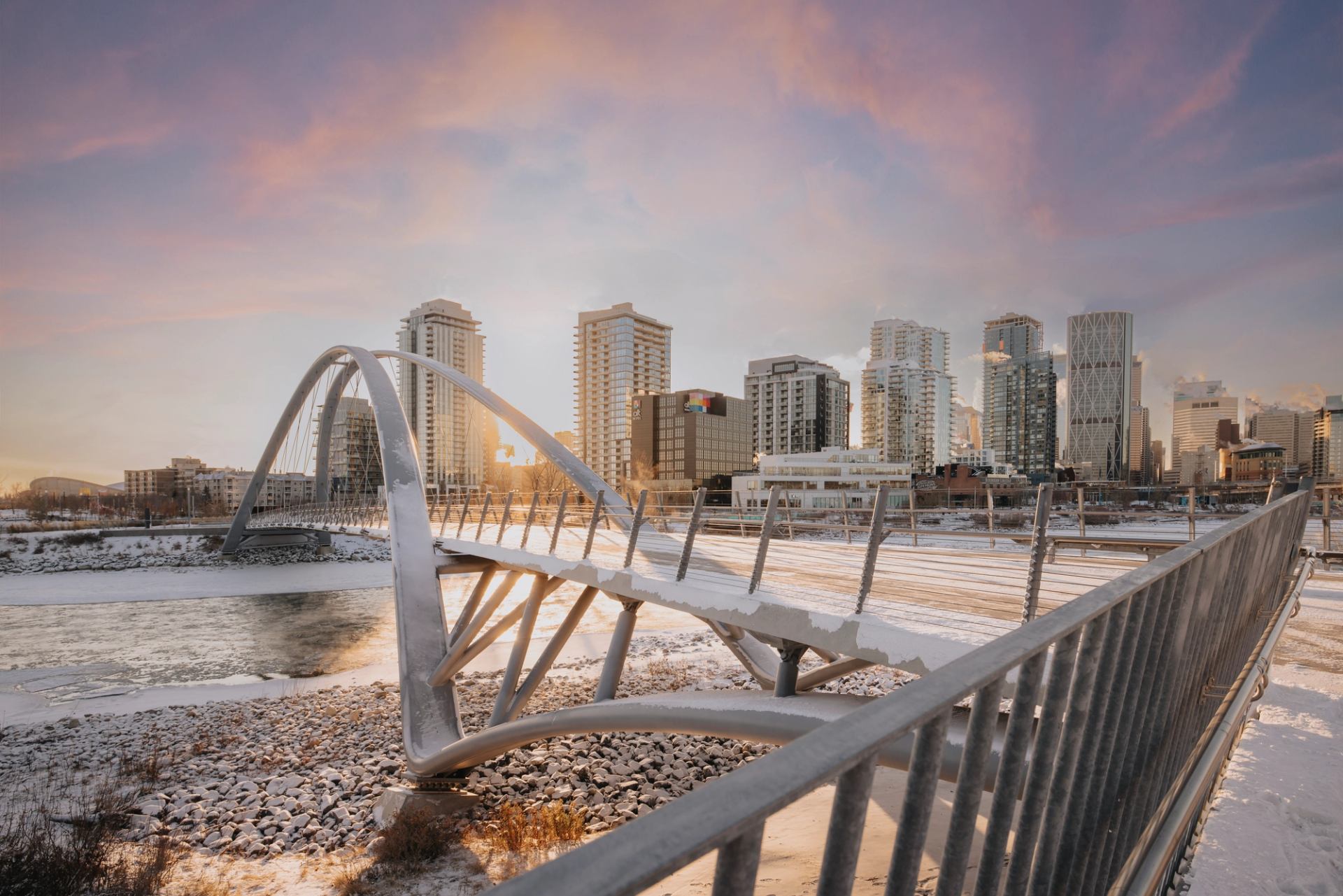 The contemporary George C. King pedestrian bridge over the Bow River in winter at sunrise with Calgary's downtown behind