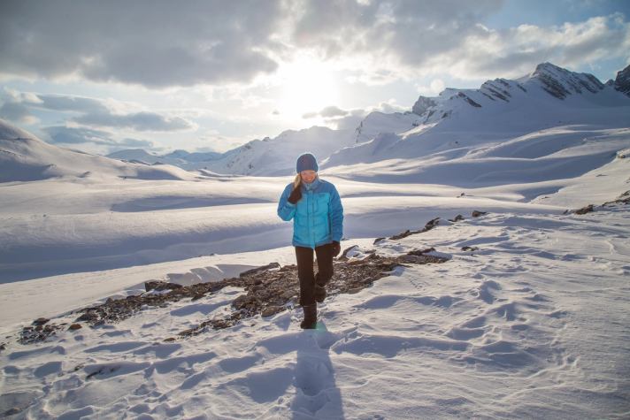 Person hiking in a snow draped landscape in the backcountry.