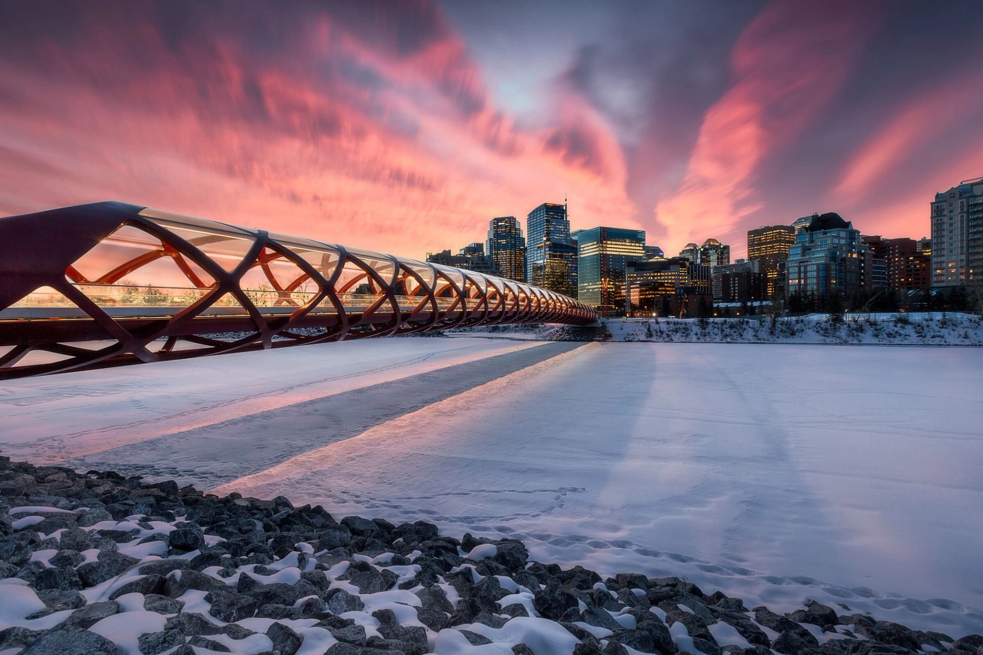 Sunset scene of the Peace Bridge on top of a frozen Bow River.