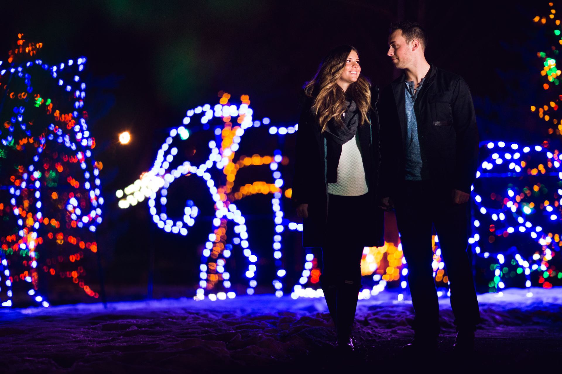 Couple walking through lit up displays at night.