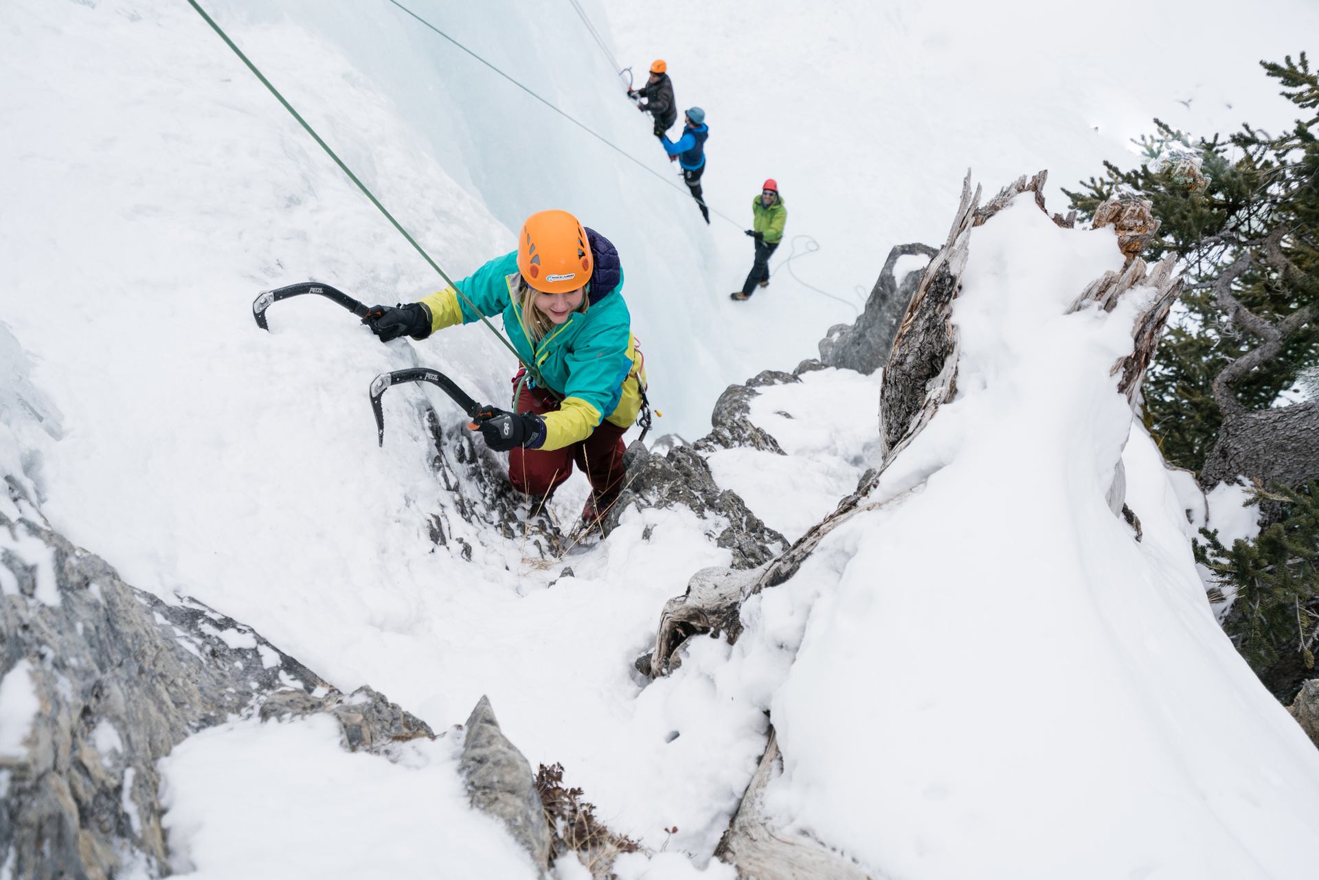 An ice climber ascending with other climbers at the base, while ice climbing at Tangle Falls in Jasper National Park