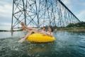 A young couple rafting near a bridge over the Oldman River near Lethbridge
