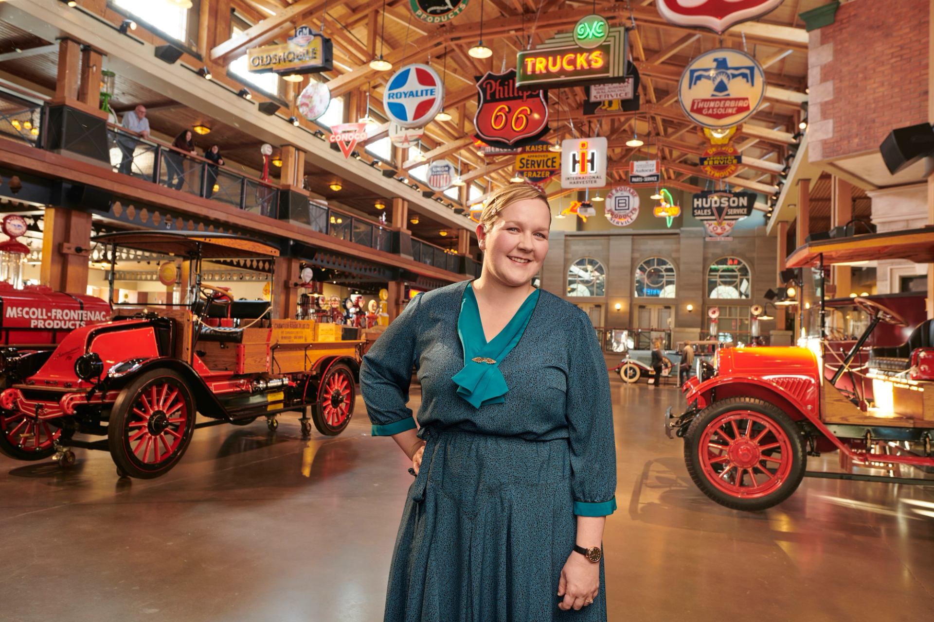 A woman stands in front of vehicles in the Gasoline Alley Museum at Heritage Park Historical Village.