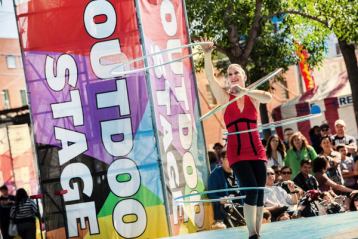 Spectators watching a hula hoop performer at an outdoor festival