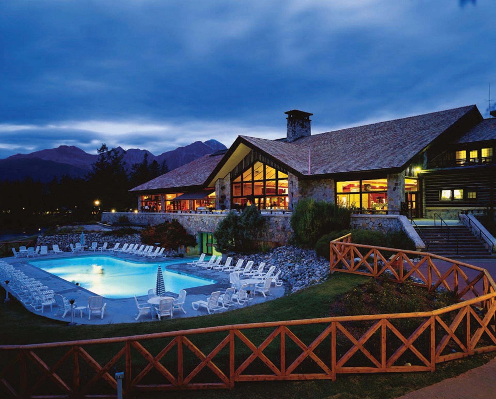 Exterior of lodge with an outdoor swimming pool at night.