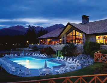 Exterior of lodge with an outdoor swimming pool at night.